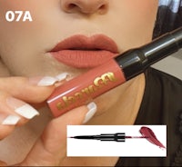 a woman is holding a lipstick and a brush